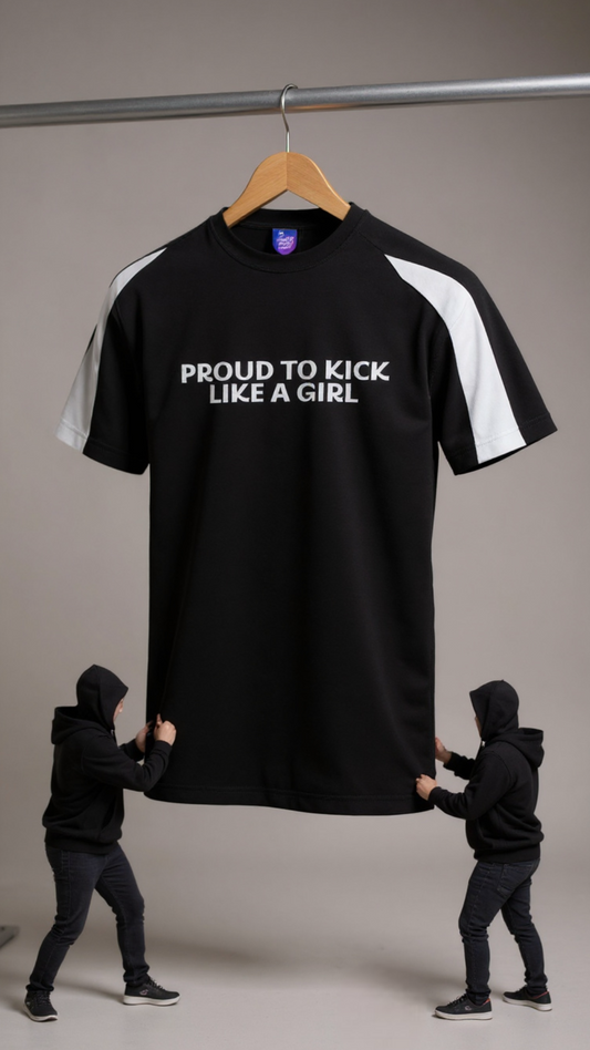 Black t-shirt with 'PROUD TO KICK LIKE A GIRL' text on a hanger, with two people holding it.